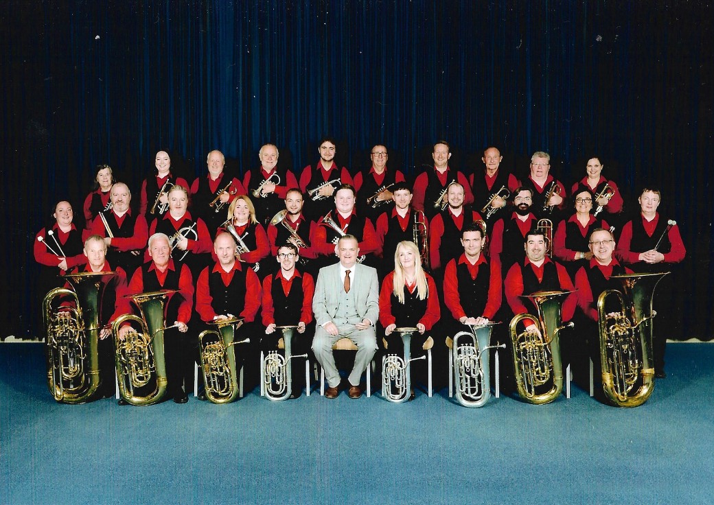 The Tyldesley Brass Band pose in three rows for an official photograph.